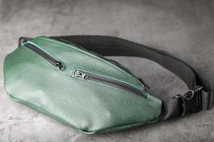 sac ceinture en cuir texturé vert foncé, banane sur fond gris. photo