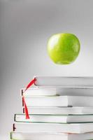 une pomme verte plane au-dessus d'isoler des livres sur un fond blanc. photo