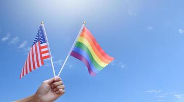 drapeau arc-en-ciel et drapeau national des états-unis d'amérique tenant à la main, mise au point douce et sélective, concept pour la célébration du mois de la fierté lgbtq dans le monde entier. photo