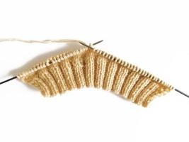 tricoter sur des aiguilles à tricoter en laine beige sur fond blanc photo
