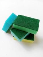 Lave-éponges de cuisine multicolores avec récureur vert abrasif sur fond blanc photo