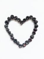 coeur de framboise noire. la figure du coeur est bordée de baies de framboises noires mûres sur fond blanc. photo