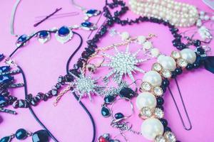 beaux bijoux brillants précieux ensemble de bijoux glamour tendance, collier, boucles d'oreilles, bagues, chaînes, broches avec perles et diamants sur fond violet rose. mise à plat, vue de dessus, lieu de copie photo