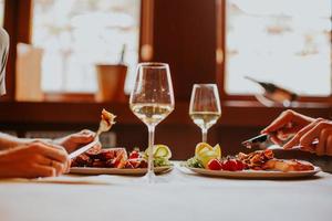 jeune couple en train de déjeuner avec du vin blanc au restaurant photo