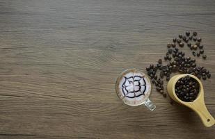 café dans un verre transparent avec écran à grain de bois et grains de café dans une cuillère photo