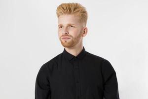 gros plan sur un jeune homme rousse avec une barbe rouge en chemise élégante noire isolée sur fond gris. concept de coupe de cheveux et de soins capillaires pour hommes à la mode. beau mec européen réussi et confiant en tenue décontractée photo