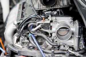 gros plan de l'ancien corps de papillon de la voiture dans la salle des machines avec de la poussière et de la suie pour réparation et nettoyage en cours avec la salle des machines photo