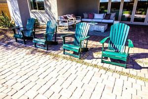 Quatre fauteuils de pelouse verte sur le patio pavé arrière-cour
