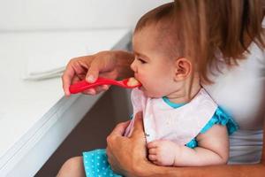 mère nourrissant une jolie petite fille en purée de légumes à partir d'une cuillère. nutrition saine pour les petits enfants photo