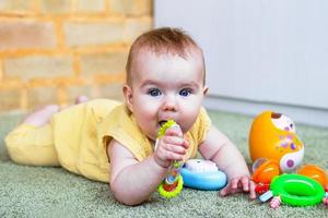 jolie petite fille allongée sur le sol et jouant avec des jouets en plastique et en bois colorés. développer la motricité de l'enfant. photo