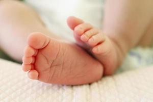 petits pieds délicats de bébé nouveau-né sur un lit blanc. photo