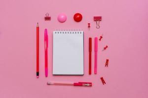 le cahier blanc se trouve sous la forme d'un blanc sur fond rose avec un stylo rouge photo