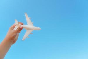 un avion blanc dans la main d'un enfant contre un ciel bleu. le concept d'un rêve de voyage et de vols. photo