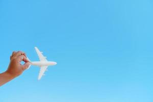 un avion blanc dans la main d'un enfant contre un ciel bleu. le concept d'un rêve de voyage et de vols. photo