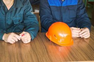 un homme travaillant comme ingénieur avec un casque jaune orange sur la table étudie, écrit dans un cahier dans une usine industrielle photo