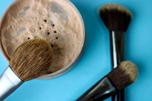 boîte de beauté, poudre minérale mate friable avec une belle brosse en bois brune spéciale de la sieste naturelle pour le maquillage sur un fond bleu chaud photo