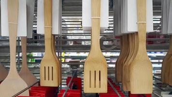 de nombreuses louches et spatules en bois marron suspendues à vendre au magasin d'ustensiles de cuisine. ustensile pour la cuisson des aliments et fabriqué avec des matériaux naturels. vente au détail d'objets dans un grand magasin photo