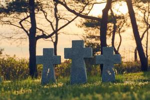 croix de pierre au coucher du soleil dans le cimetière militaire allemand, europe photo