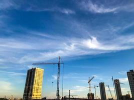 les grues de construction érigent de nouvelles maisons à partir de blocs. constructions neuves, lieux de vie des personnes. dans les maisons vitrage panoramique, différentes couleurs de décoration de façade photo