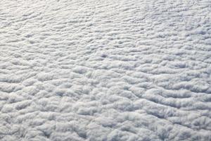 vue à couper le souffle sur les nuages depuis la fenêtre de l'avion, d'épais nuages bleus blancs ressemblent à de la mousse souple photo