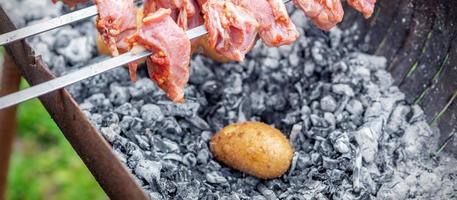 l'homme prépare la viande de barbecue avec des pommes de terre photo