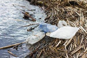 bouteilles en plastique sur la rive du fleuve, concept pour la journée de la protection des océans. déchets plastiques non dégradables sur la côte. photo