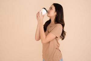 heureuse jeune femme tenant une tasse de café debout dans le studio photo