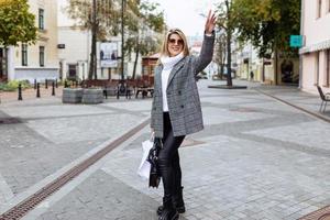 femme d'affaires adulte dans des vêtements d'automne élégants attrape un taxi dans la ville photo