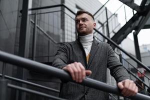 portrait brutal d'un homme d'âge moyen sur un escalier en métal gris près d'un immeuble moderne photo