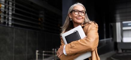 portrait d'une femme d'affaires âgée avec un ordinateur portable dans des verres à l'extérieur du bureau, concept de femme forte et indépendante photo