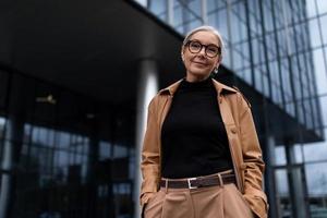 femme d'affaires senior sur le fond d'un immeuble de bureaux regarde la caméra avec un sourire photo