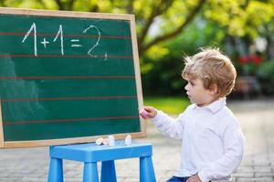 petit garçon au tableau noir pratiquant les mathématiques