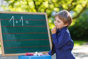 petit garçon au tableau noir pratiquant les mathématiques