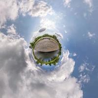 petite planète dans un ciel couvert bleu avec de beaux nuages avec transformation du panorama sphérique à 360 degrés. vue aérienne abstraite sphérique. courbure de l'espace. photo