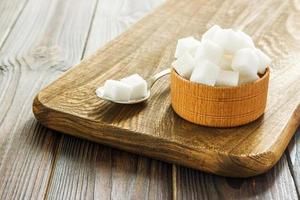 Bol et cuillère pleine de sucre sur fond de bois photo