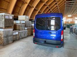 un minibus bleu dans un entrepôt d'équipements et de matériaux industriels. concept livraison, logistique, incoterms dap, dpp conditions de livraison photo