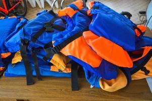 des gilets de sauvetage en caoutchouc bleu vif multicolores remplis d'air et en caoutchouc mousse pour la protection des personnes qui se noient sont allongés sur la table photo