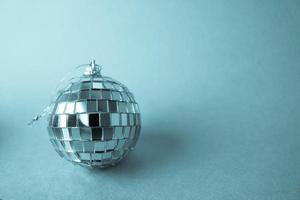 miroir argenté club musical boule disco petit verre rond hiver brillant décoratif belle boule de noël festive de noël, jouet de noël collé sur des étincelles sur fond bleu photo