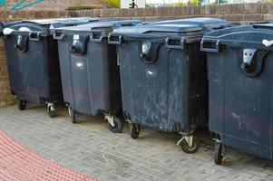 les poubelles sont en ville. conteneurs noirs de grande capacité pour stocker diverses ordures dans le centre-ville. collecte séparée des déchets secondaires et des produits de réparation photo