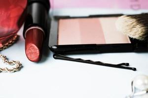 ensemble de cosmétiques féminins de rouge à lèvres, surligneur, crayon à lèvres, pinceaux, pinceaux, parfum, poudre, bijoux sur fond bleu. boîte de beauté mise à plat. vue de dessus photo