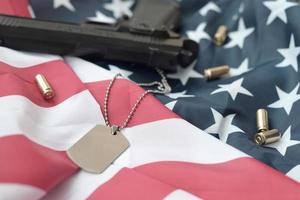 jeton d'étiquette de chien de l'armée avec des balles de 9 mm et un pistolet se trouvent sur le drapeau des états-unis plié photo