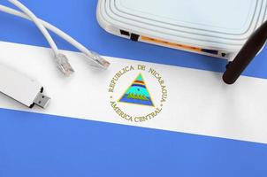 drapeau du nicaragua représenté sur une table avec un câble internet rj45, un adaptateur wifi usb sans fil et un routeur. notion de connexion internet photo