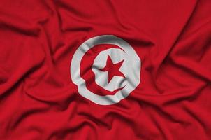 le drapeau tunisien est représenté sur un tissu de sport avec de nombreux plis. bannière de l'équipe sportive photo