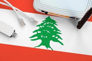 drapeau du liban représenté sur une table avec câble internet rj45, adaptateur wifi usb sans fil et routeur. notion de connexion internet photo