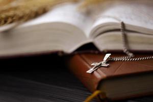 collier en argent avec croix crucifix sur le livre chrétien de la sainte bible sur une table en bois noire. demander des bénédictions à Dieu avec le pouvoir de la sainteté photo