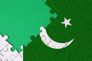 le drapeau du pakistan est représenté sur un puzzle terminé avec un espace de copie vert gratuit sur le côté gauche photo