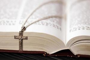 collier en argent avec croix crucifix sur le livre chrétien de la sainte bible sur une table en bois noire. demander des bénédictions à Dieu avec le pouvoir de la sainteté, ce qui porte chance photo