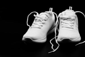 une paire de baskets femme neuves blanches sur fond noir photo
