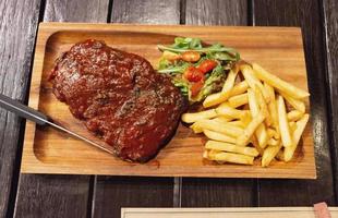 vue de dessus des côtes de porc barbecue avec frites et tomates sur plaque de bois photo