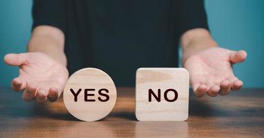 symbole de choix oui ou non. main faisant un geste de question pour choisir entre deux cubes avec icône oui et non sur le bureau. affaires et concept de choix oui ou non. photo